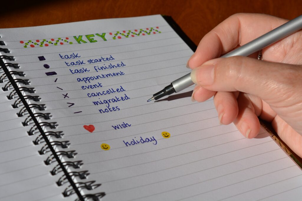 Woman writing in a bullet journal, close up, pen in hand